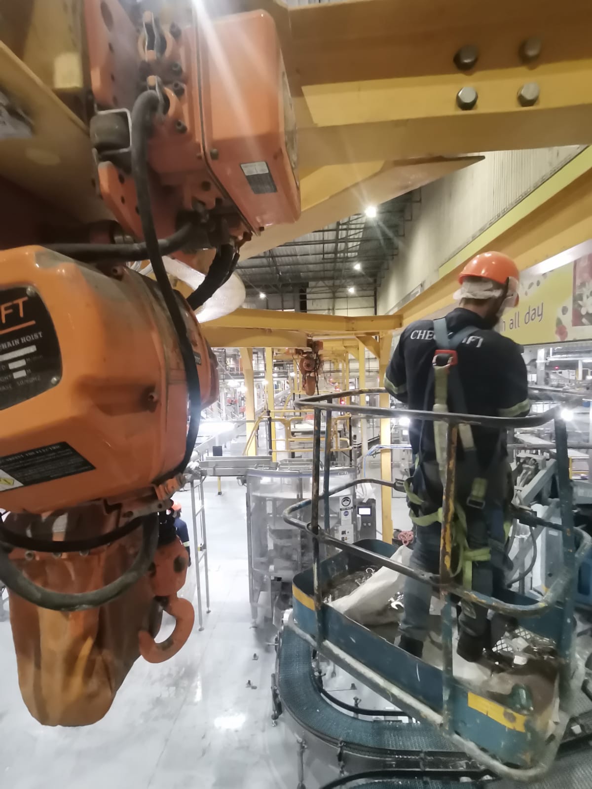 Technician on boom lift installing chain hoist