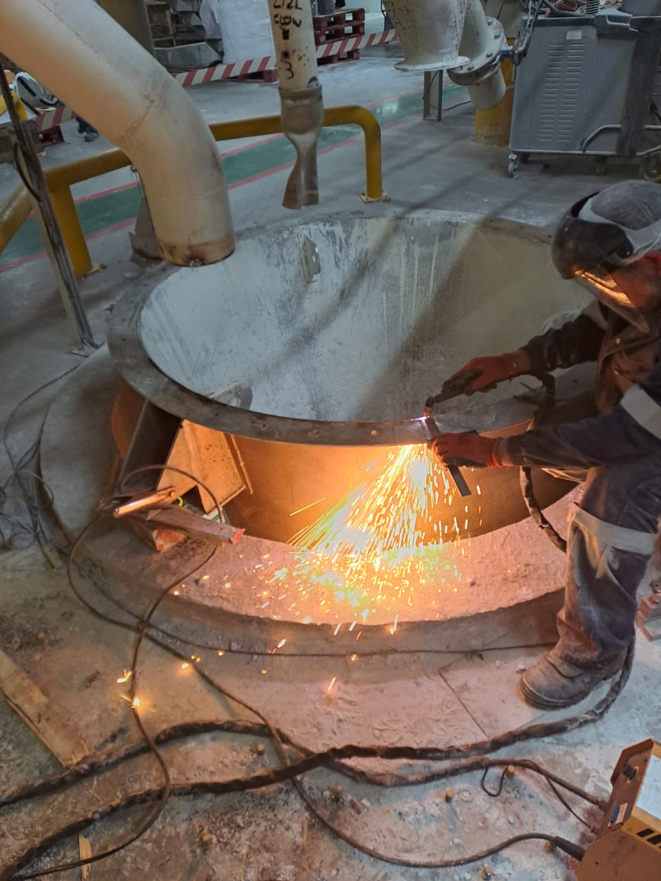 Welder cutting steel vessel with sparks flying