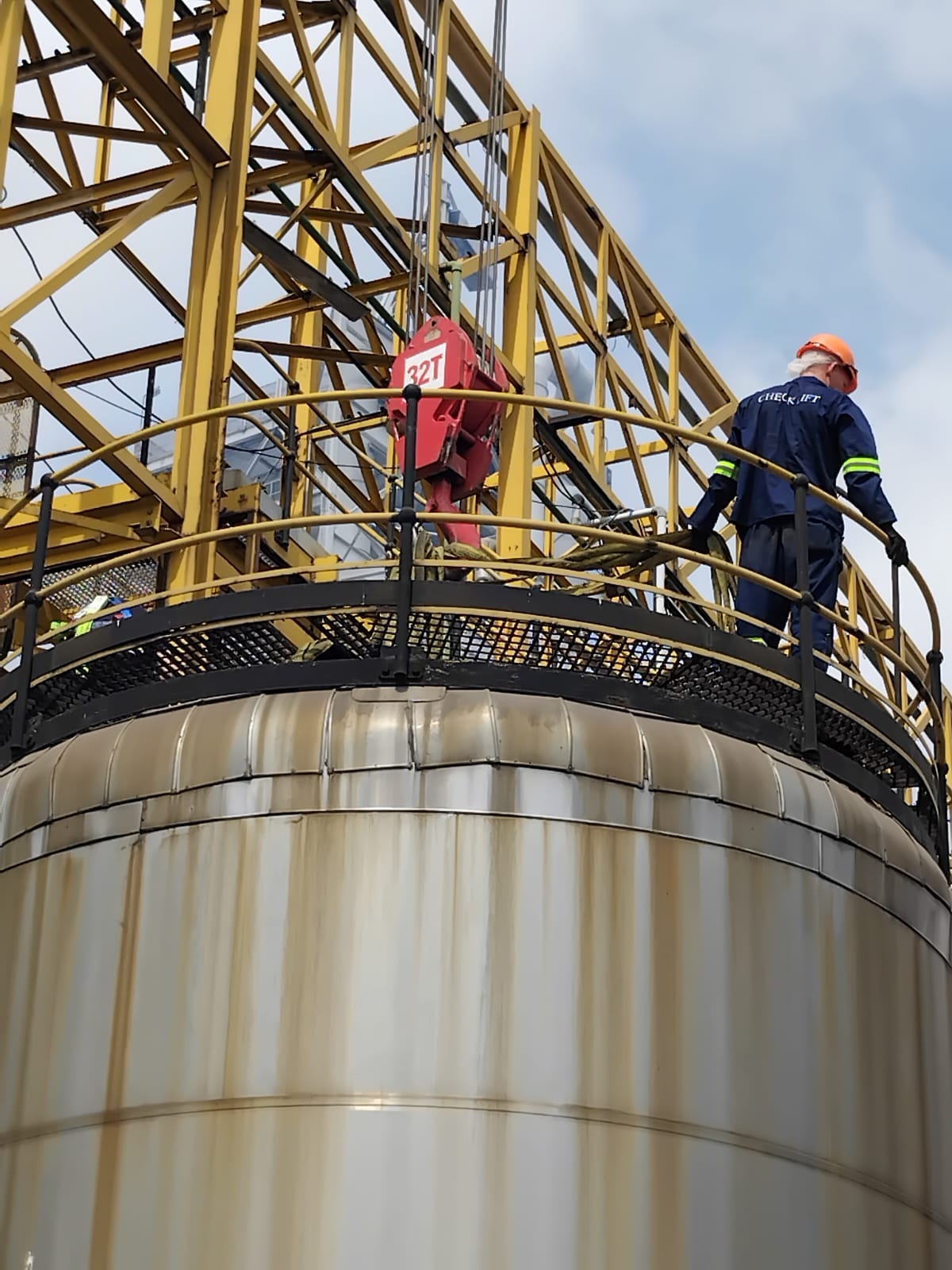 Technician on tank top guiding crane hook