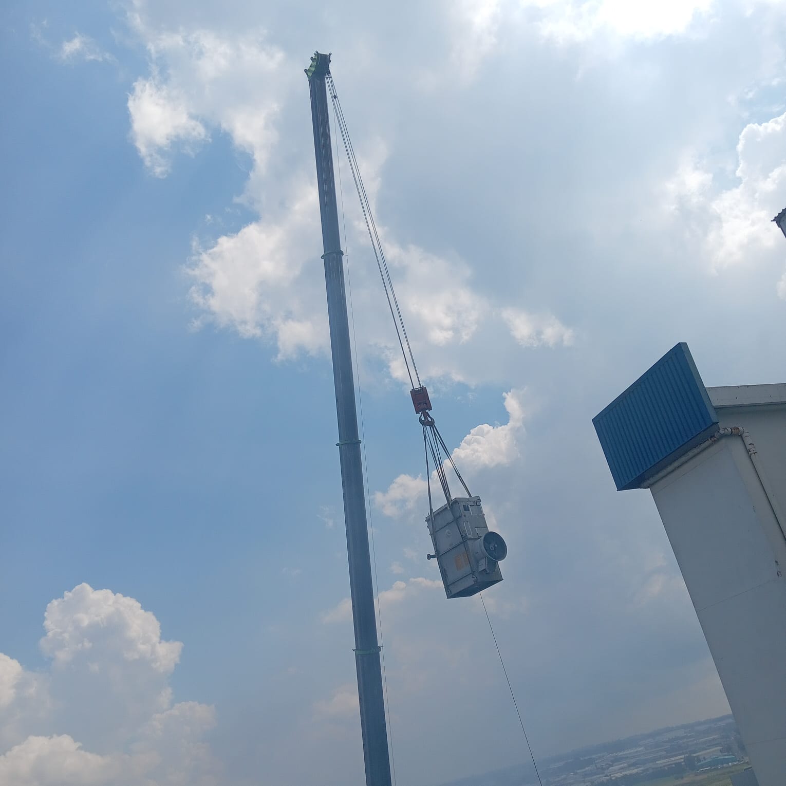 Crane lifting equipment against a cloudy sky