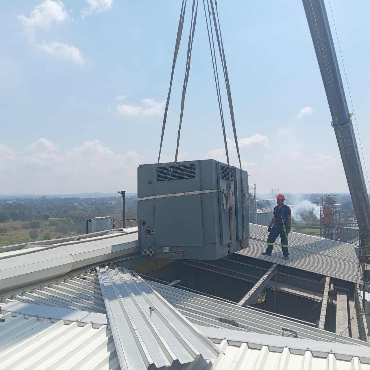 Equipment being lowered onto rooftop with technician guiding